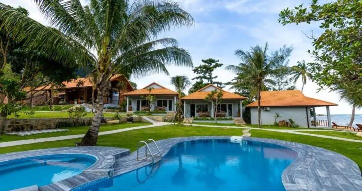 Aerial view of a tropical luxury resort with palm trees, infinity pool, and oceanfront, highlighting budget-friendly travel in 2025