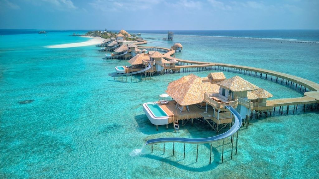 Elegant beachfront resort with lounge chairs, crystal-clear water, and sunset view, representing top affordable luxury resorts in 2025