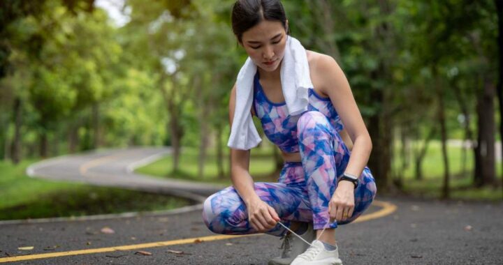 Athletic young woman tying shoelaces before exercising outdoors in a park