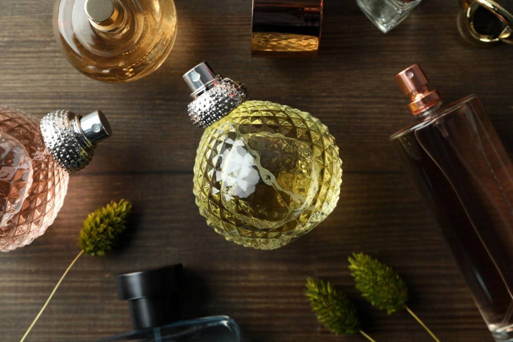 Bottles of perfumes on wooden background, top view and close up