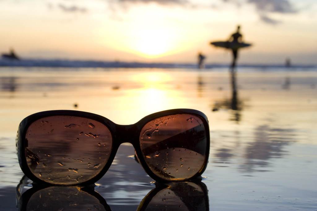 Cleaning sunglasses with microfiber cloth after beach use