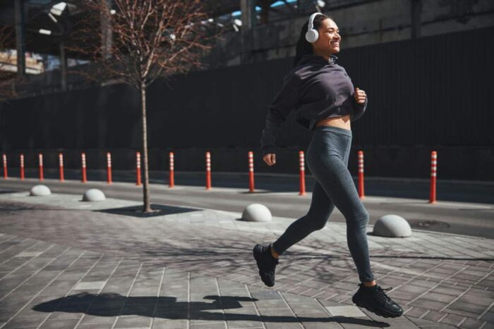 Joyful good-looking sportswoman dressed in activewear jogging in the morning