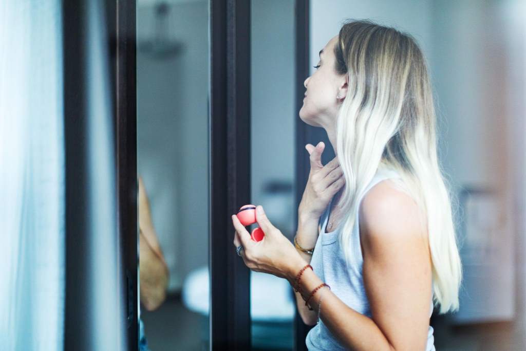Mid adult woman applying perfume at home in the morning