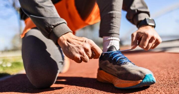 Sports man tying running shoes before workout