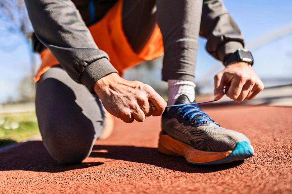Sports man tying running shoes before workout