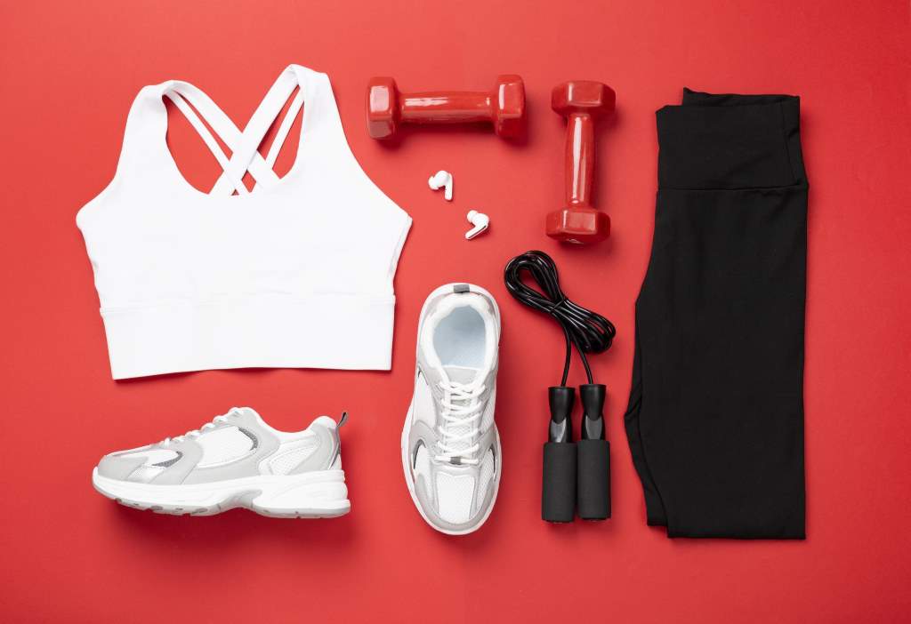 Woman sportwear outfit with equipment on color background, top view